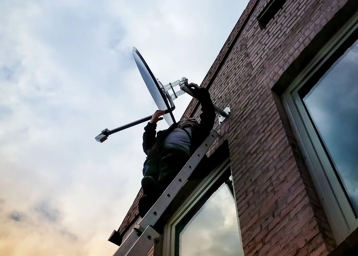 Antena instalada en el frente de una casa, con una escalera apoyada durante el montaje